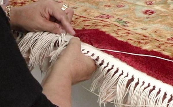 The fringes are being sewn on by hand