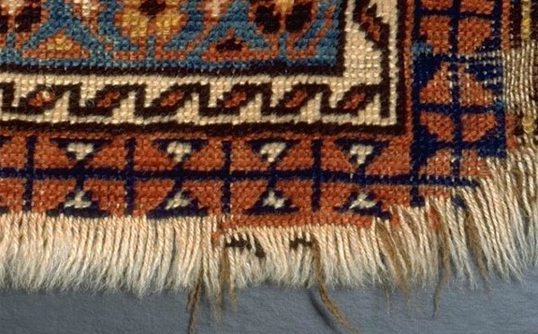 Before repair, this rug is worn on the ends. The process we recommend for a rug like this is called unravel and overcast
